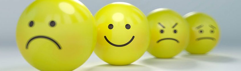 Sentiment Analysis: Palle di gomma gialle che rappresentano vari smiley su tavolo bianco
