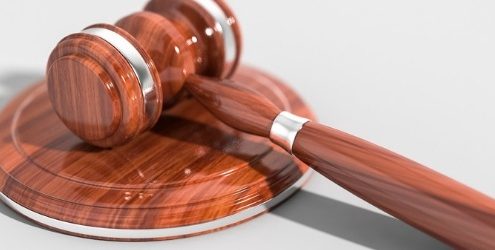 sanzioni: martelletto del giudice in legno lucido su sfondo bianco