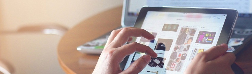 Insight consumatori 2018: donna che sta scorrendo una pagina di e-commerce su un tablet su sfondo di un tavolo con sopra un computer aperto sulla pagina dell'e-mail personale