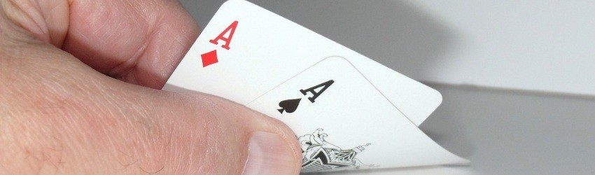 chiave della Vendita: mano di uomo che mostra due assi sollevando leggermente le carte da gioco dal tavolo