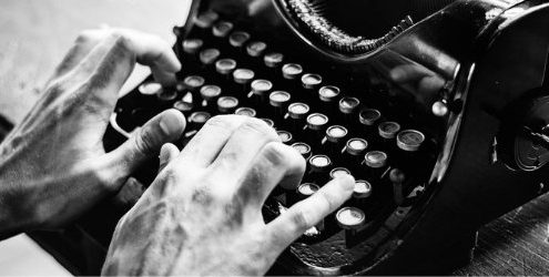 contenuti per i social: mani di uomo che battono sulla tastiera di una macchina da scrivere antica