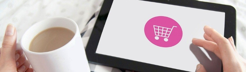 UE nuove regole prodotti digitali: donna rilassata sul divano che fa shopping online con un tablet e una tazza nell'altra mano